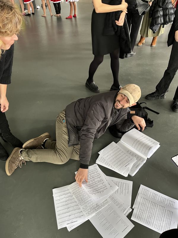 Albert en el suelo ordenando partituras durante un ensayo