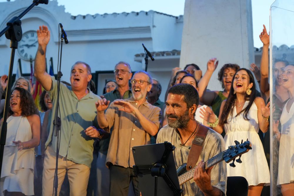 Coro y músicos al aire libre con los brazos en alto