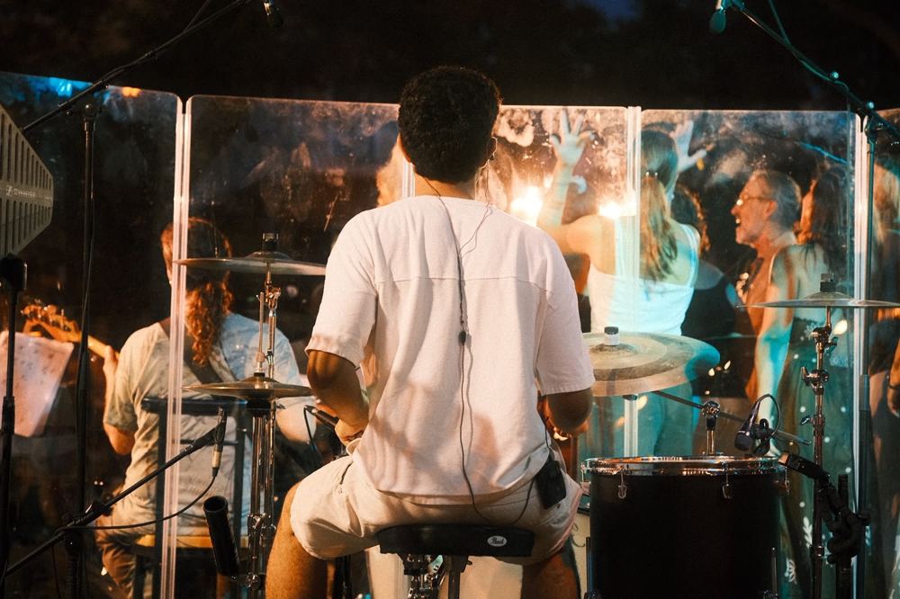 El batería tocando tras la mampara