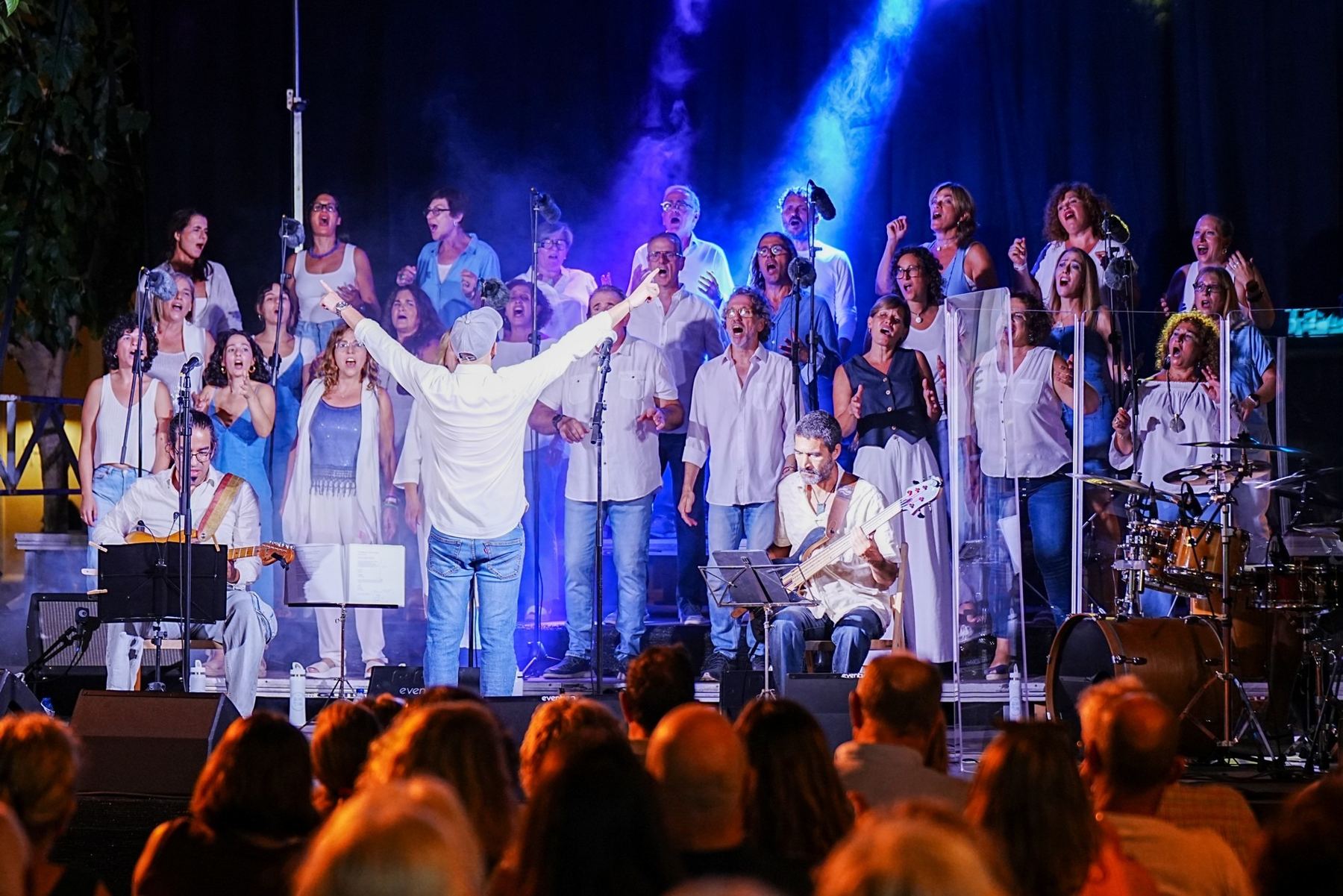 El coro con los brazos en alto bajo los focos